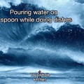 Pouring water on a spoon while doing dishes