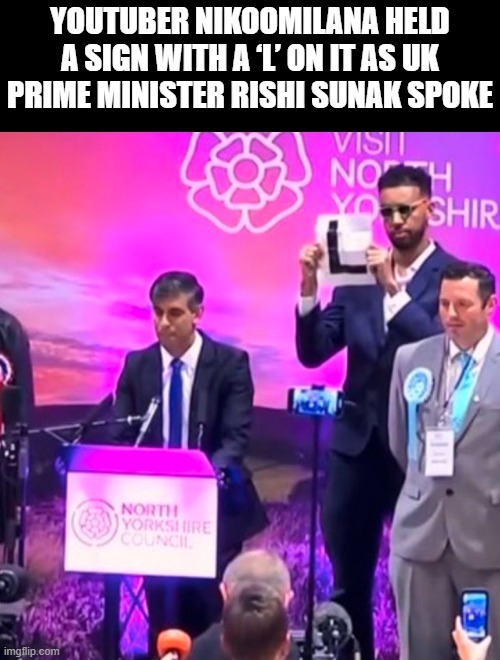 YouTuber Niko Omilana held a sign with a L on it as UK Prime Minister Rishi Sunak spoke - meme